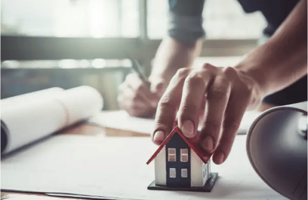 a person holding a miniature house while writing